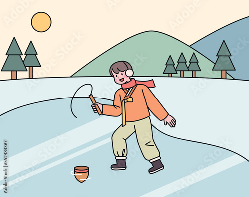 A boy wearing a hanbok in the cold winter is playing tops on the ice.