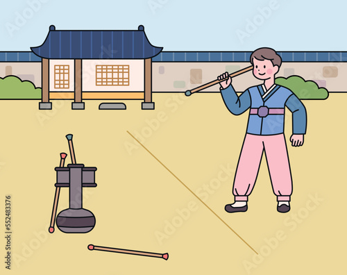 A boy wearing a hanbok is playing arrow throwing. Korean traditional game.