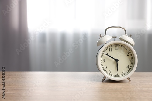 White alarm clock on wooden table indoors, space for text