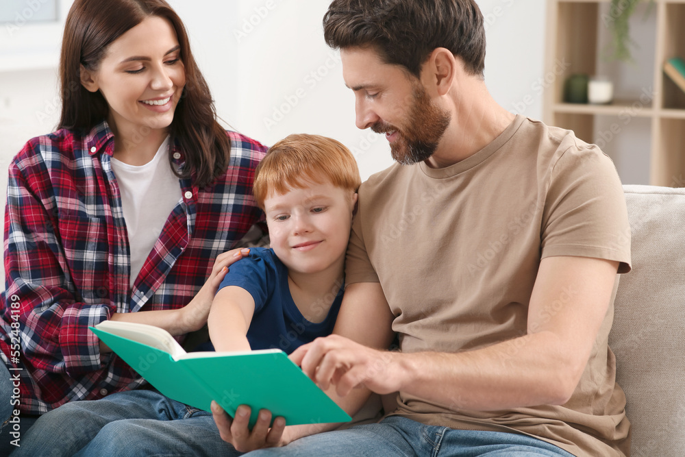 Happy parents with their child reading book on couch at home Happy parents with their child reading book on couch at home