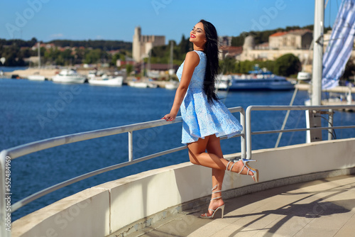Beautiful young woman in a blue dress is enjoying the sun by the sea © joycedragan