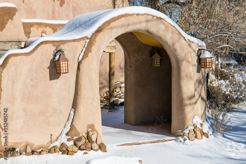 Arched entrance in snow-covered adobe wall in Santa Fe, New Mexico