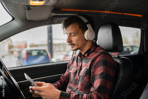 man with headphones listen music or podcast in car use mobile phone © Miljan Živković