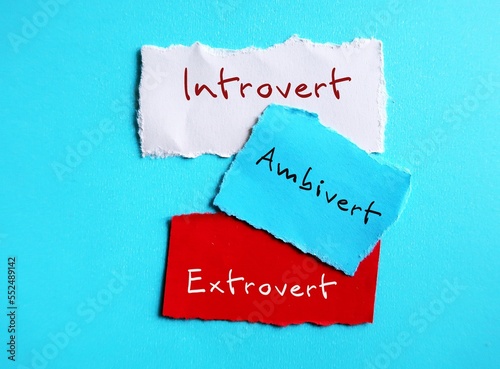 Torn paper on blue background with handwritten text - INTROVERT EXTROVERT AMBIVERT, Introverts tend to feel drained after socializing while extroverts tend to feel energized, ambivert is in the middle