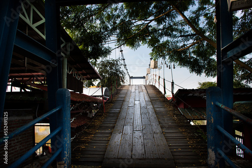 Fototapeta Naklejka Na Ścianę i Meble -  Suspension wooden bridge for thai people and foreign traveler walking cross river canal to travel visit Sai Noi floating street market at Wat Sai Yai temple on November 22, 2018 in Nonthaburi Thailand