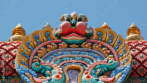Minor demon adorns the top of colorful Hindu temple photo