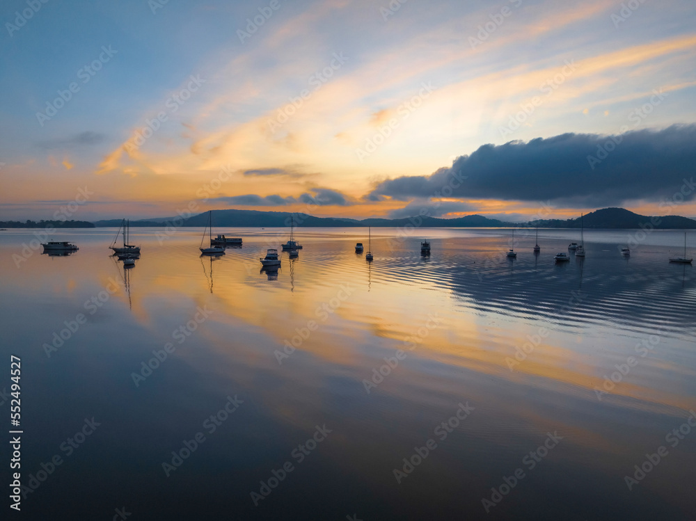 Sunrise over the water with fog, boats, clouds and reflections