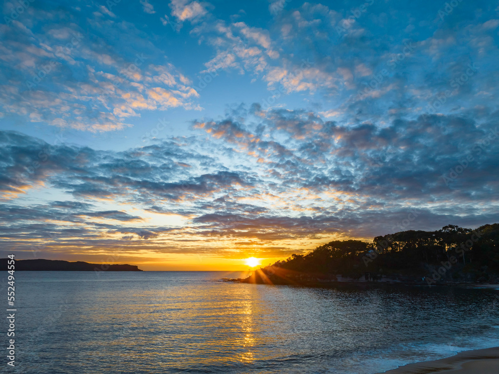 Aerial sunrise seascape with calm seas and a mix of low and medium clouds