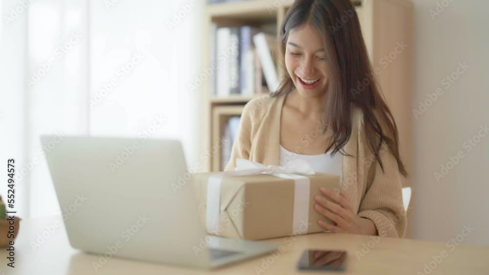 Young asian woman using computer laptop at home. Female showing gift box while on video conversation with friend. Happy birthday, Happy new year, Thanksgiving Young asian woman using computer laptop at home. Female showing gift box while on video conversation with friend. Happy birthday, Happy new year, Thanksgiving