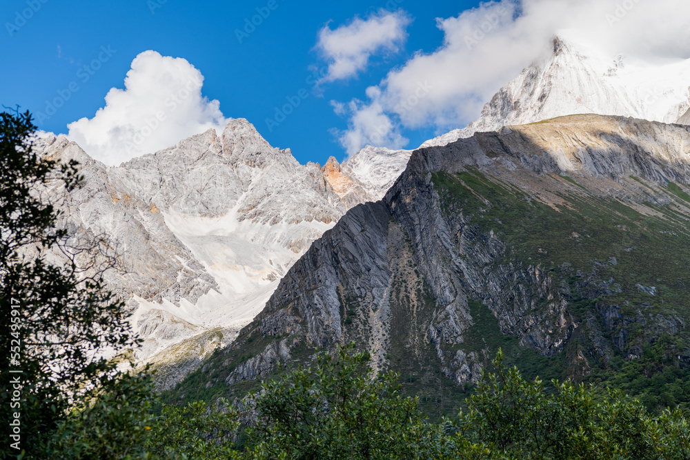Snow mountain range with pathway of trail route to Milk lake background in nice sky day in summer season at Yading National Park, Daocheng, Sichuan, China