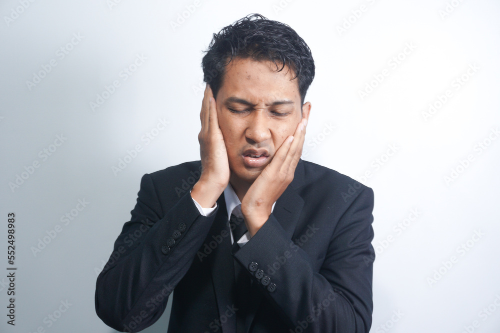 Tooth ache concept. Indoor shot of young male feeling pain, holding his cheek with hand, suffering from bad toothache, looking at camera with painful expression Tooth ache concept. Indoor shot of young male feeling pain, holding his cheek with hand, suffering from bad toothache, looking at camera with painful expression