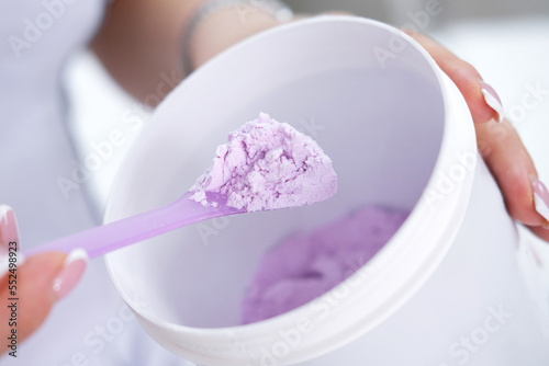 Alginate mask purple in a jar in female hands. cosmetic devices for the skin.