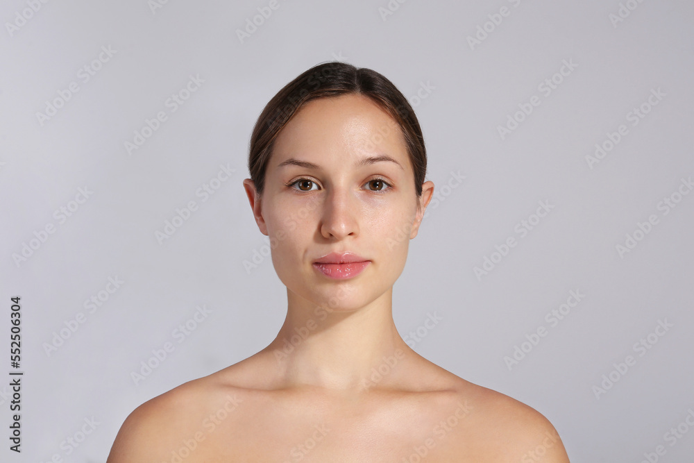 Studio portrait of young beautiful woman with long black hair tied in ponytail and clean face skin. Close up, copy space, isolated gray background. Studio portrait of young beautiful woman with long black hair tied in ponytail and clean face skin. Close up, copy space, isolated gray background.