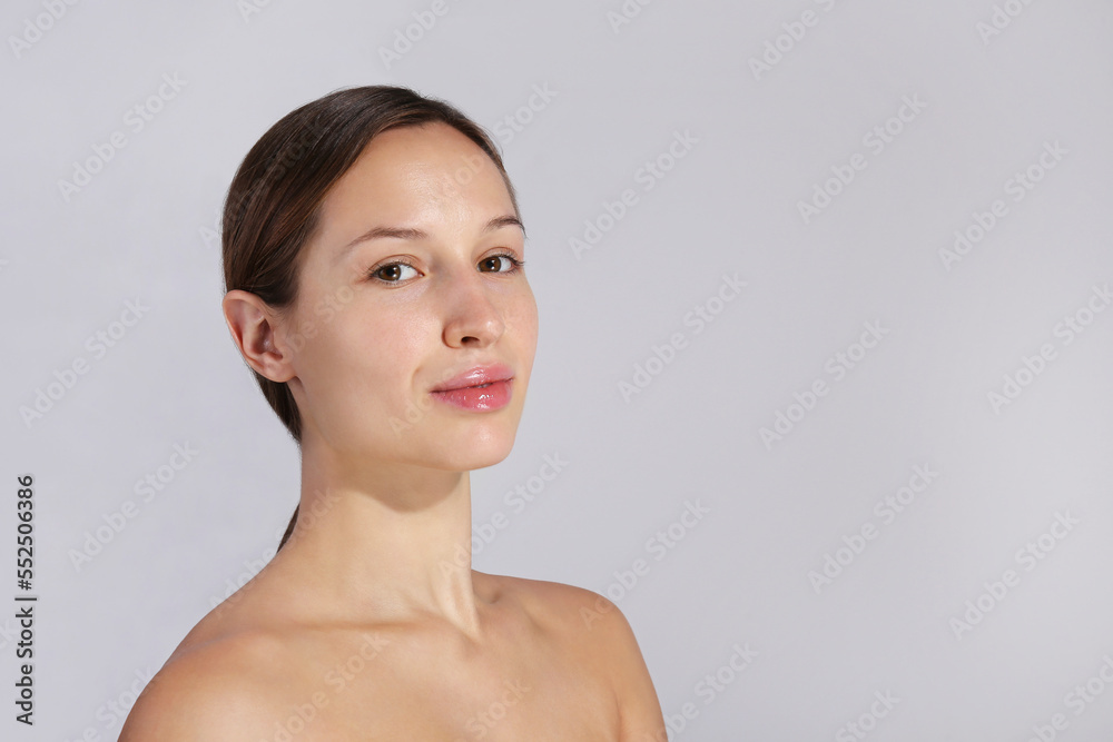 Studio portrait of young beautiful woman with long black hair tied in ponytail and clean face skin. Close up, copy space, isolated gray background. Studio portrait of young beautiful woman with long black hair tied in ponytail and clean face skin. Close up, copy space, isolated gray background.