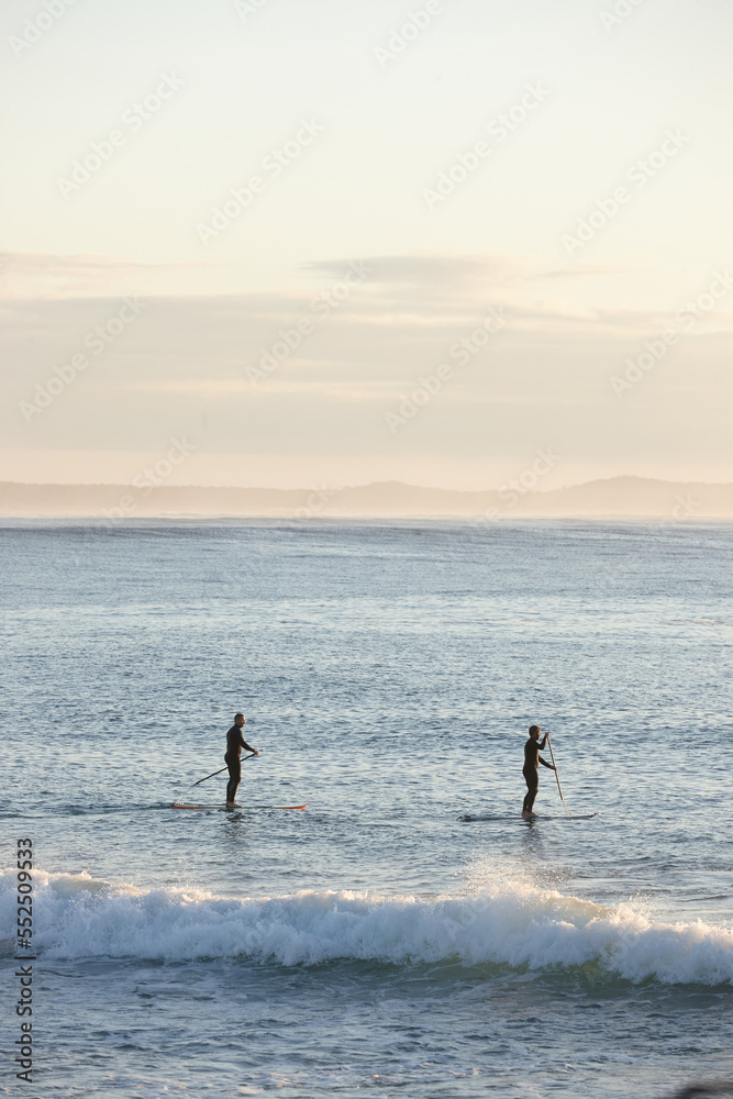 Paddle boarders on ocean at sunrise Paddle boarders on ocean at sunrise