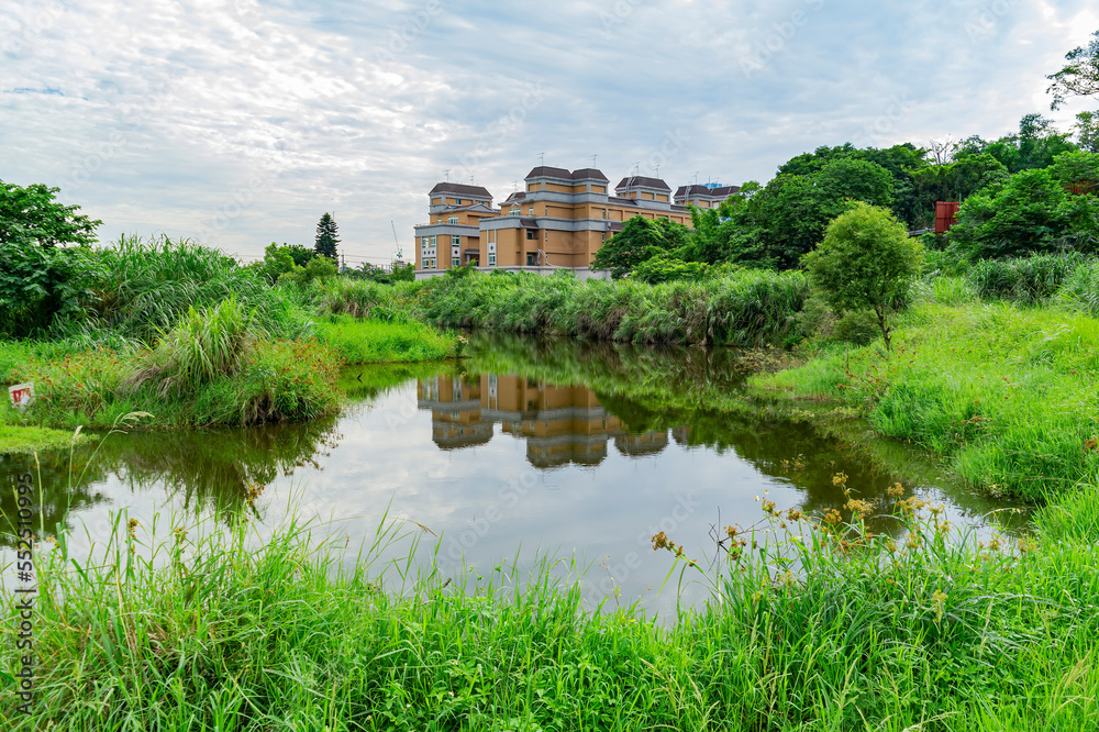 Sunny view of a pond landscape with a residence building in Xindian District