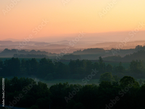 Spring hills where the dawn breaks through the morning fog