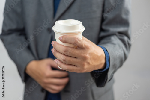 Businessman holding white paper coffee cup to take away.