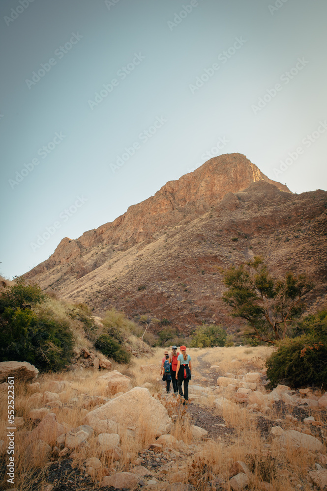 Familie wandert in der Abenddämmerung über den Olive Trail, einen Pfad im Naukluft Gebirge, Namibia