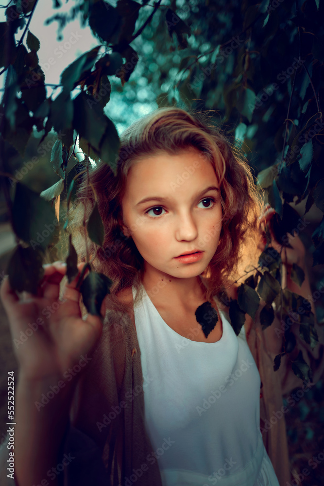 Portrait of a girl in leaves in the summer