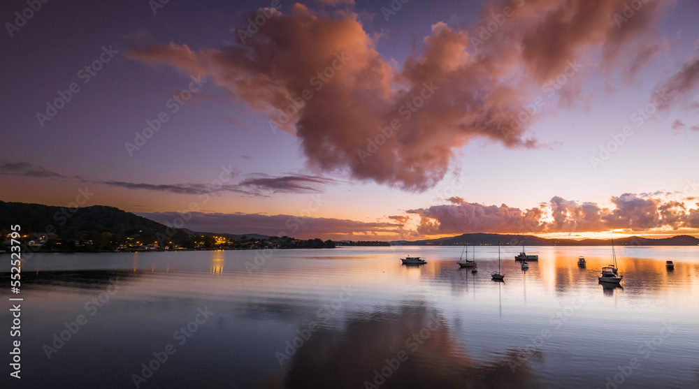 Aerial sunrise waterscape panorama with boats, clouds and reflections
