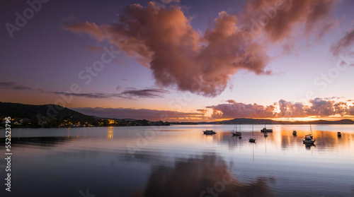 Aerial sunrise waterscape panorama with boats, clouds and reflections