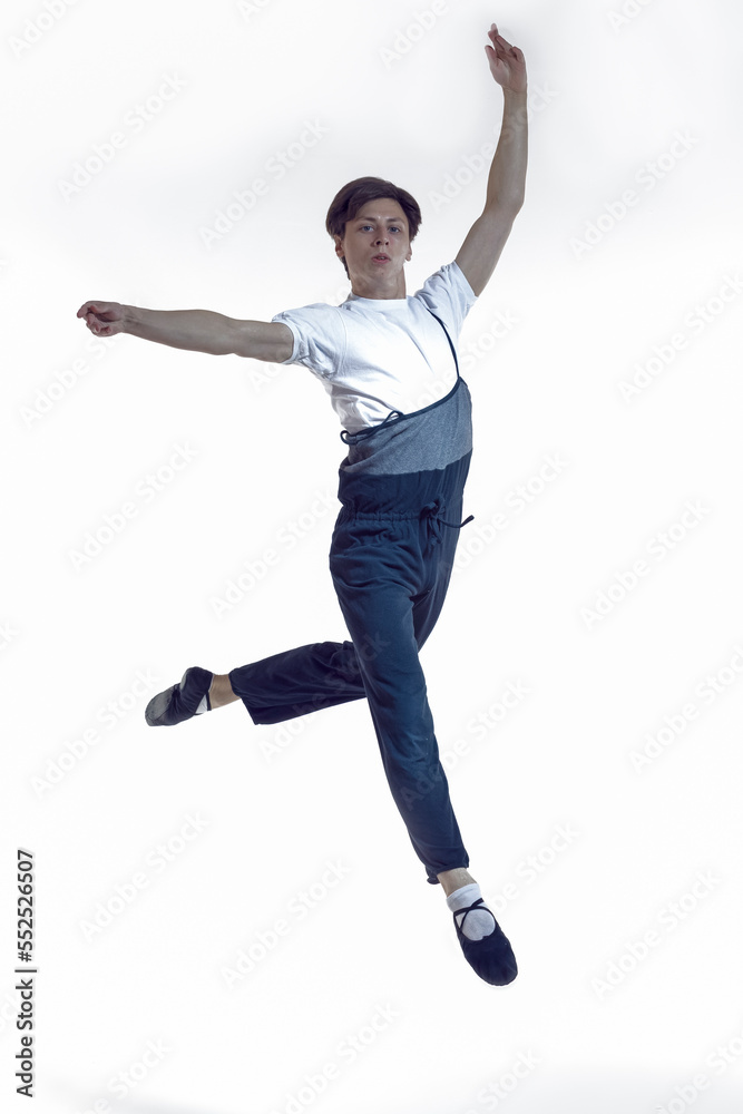 Professional Dancing Caucasian Male Ballet Dancer Performing in Flight With Hands Outspread in Studio Over White Background.