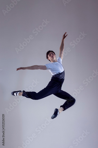 One Professional Caucasian Male Ballet Dancer Performing in Flight With Hands Outspread in Studio