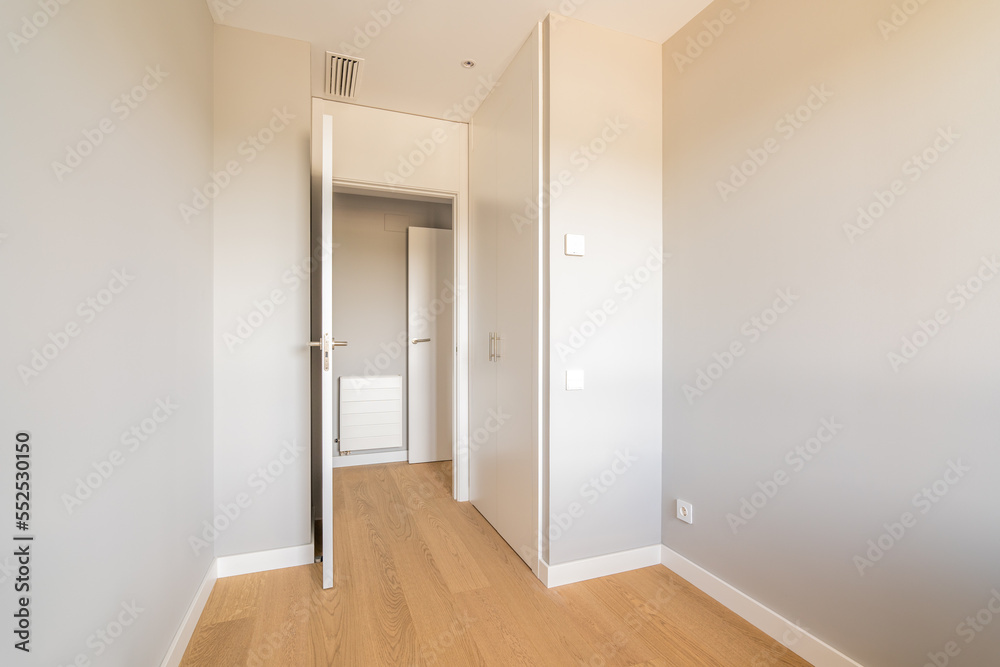 Empty room with laminate flooring and door leading to corridor. Repair and construction concept. Empty room with laminate flooring and door leading to corridor. Repair and construction concept.