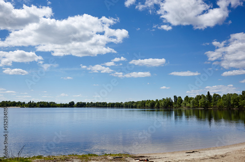 Beautiful river landscape. Lake surface on a sunny perfect day. The surface of the water against the background of trees and a blue sky. Blurred image, selective focus