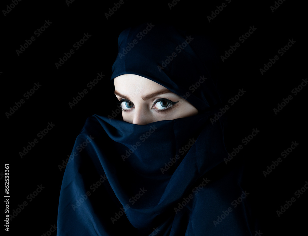 Portrait of young woman wearing hood on black background.