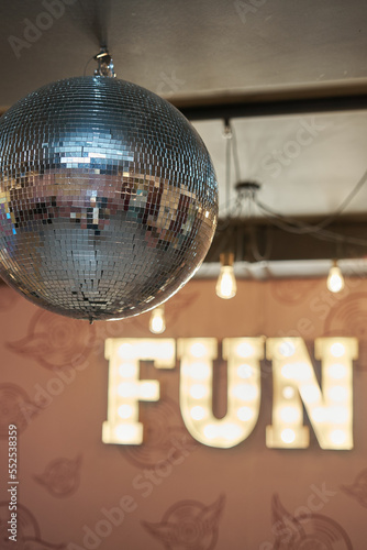 Illumination from hanging light bulbs and a sign on the wall: "fun". From the side of the disco ball.