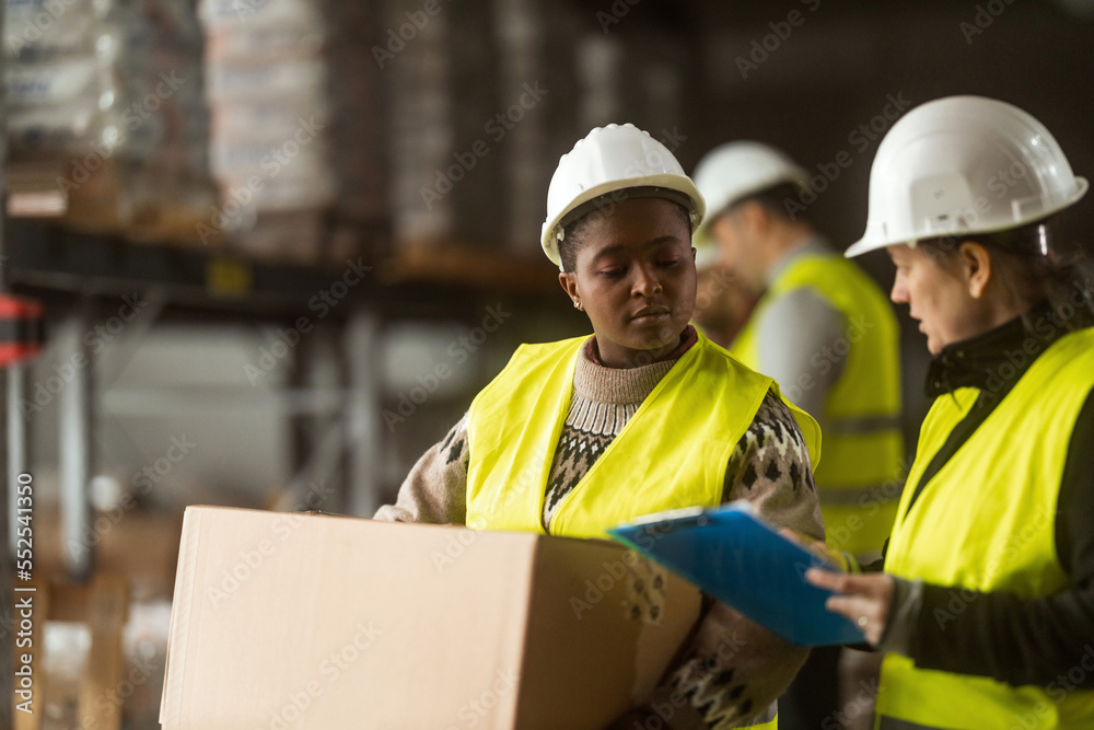 A multiracial group of people is working in a distribution warehouse, the manager is giving instructions to the workers. A multiracial group of people is working in a distribution warehouse, the manager is giving instructions to the workers.