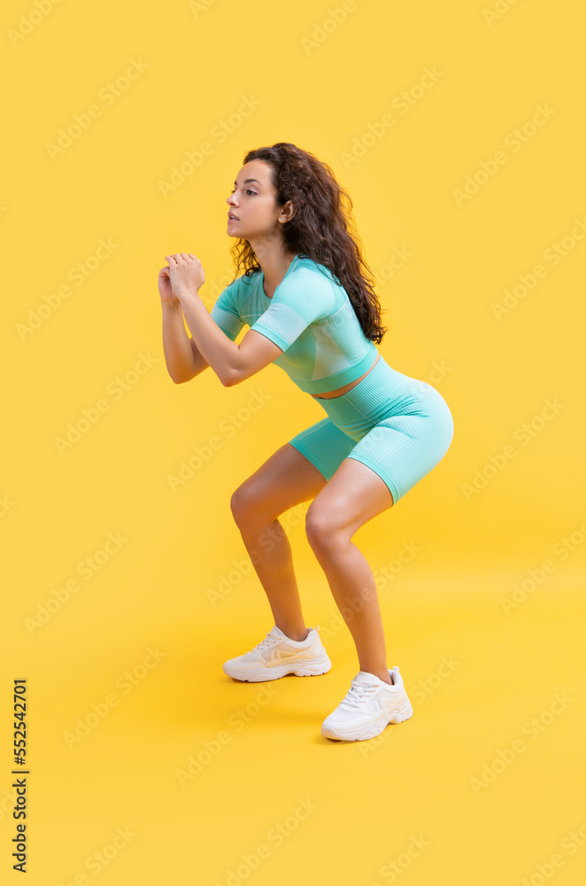 fitness woman squatting in sportswear at studio. fitness woman in sportswear squatting