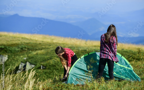 Attach necessary structural components tent. Almost done. Teamwork concept. Group friends set up tent on top mountain. Camping hiking. Hiking activity. Helpful to have partner for raising tent