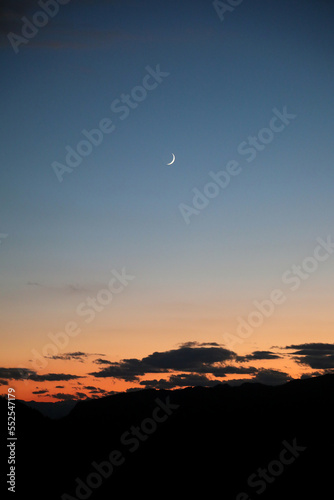 small crescent moon during sunset and the colors of the sky