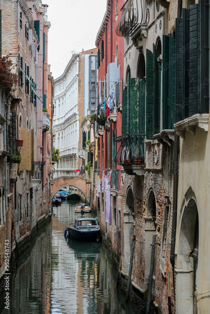 Glimpse with boats in the navigable canal among the houses of the island of Venice