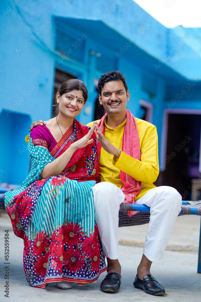 Obraz premium Happy Indian farmer with wife making home shape with hand. dream home concept.