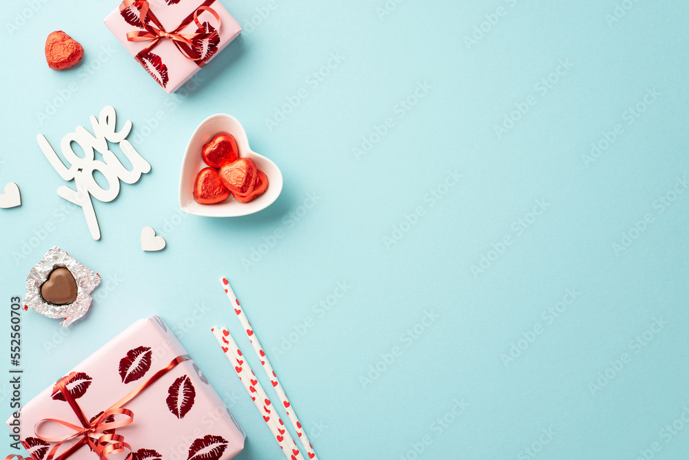 Valentine's Day concept. Top view photo of gift boxes in wrapping paper with kiss lips pattern heart shaped saucer candies straws inscription love you on isolated pastel blue background with copyspace Valentine's Day concept. Top view photo of gift boxes in wrapping paper with kiss lips pattern heart shaped saucer candies straws inscription love you on isolated pastel blue background with copyspace