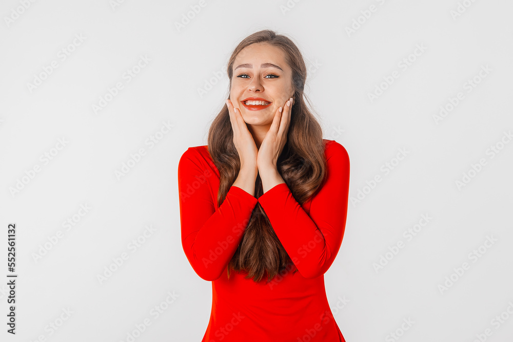 Beautiful shocked and surprised woman with open mouth. Amazed girl holds cheeks by hand, stand over white studio background. Pretty woman expresses great surprise