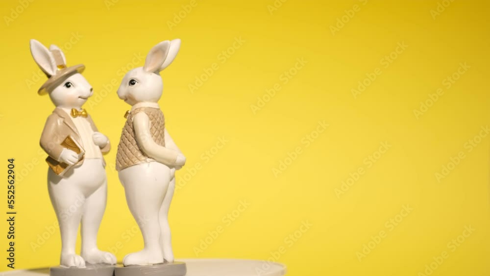 Easter figurines of rabbits on a bright yellow background. Creative decor, happy Easter