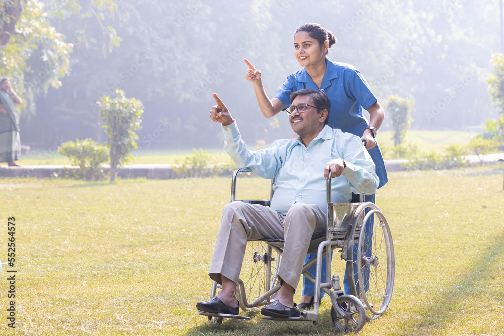 A caring nurse pushing an elderly man in a wheelchair along a pathway. A caring nurse pushing an elderly man in a wheelchair along a pathway.