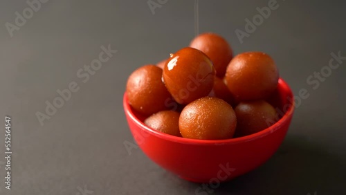 Sweet Gulab Jamun served in bowl, Famous Indian dessert sweets isolated over black indoor studio background photo