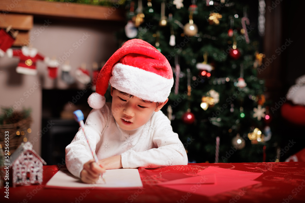 young girl wearing Santa hat was writing letter to Santa at home young girl wearing Santa hat was writing letter to Santa at home