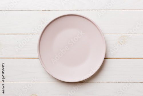 Top view of empty pink plate on wooden background. Empty space for your design