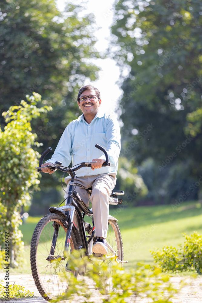 Naklejka premium Senior man enjoying and having fun riding bicycle at park