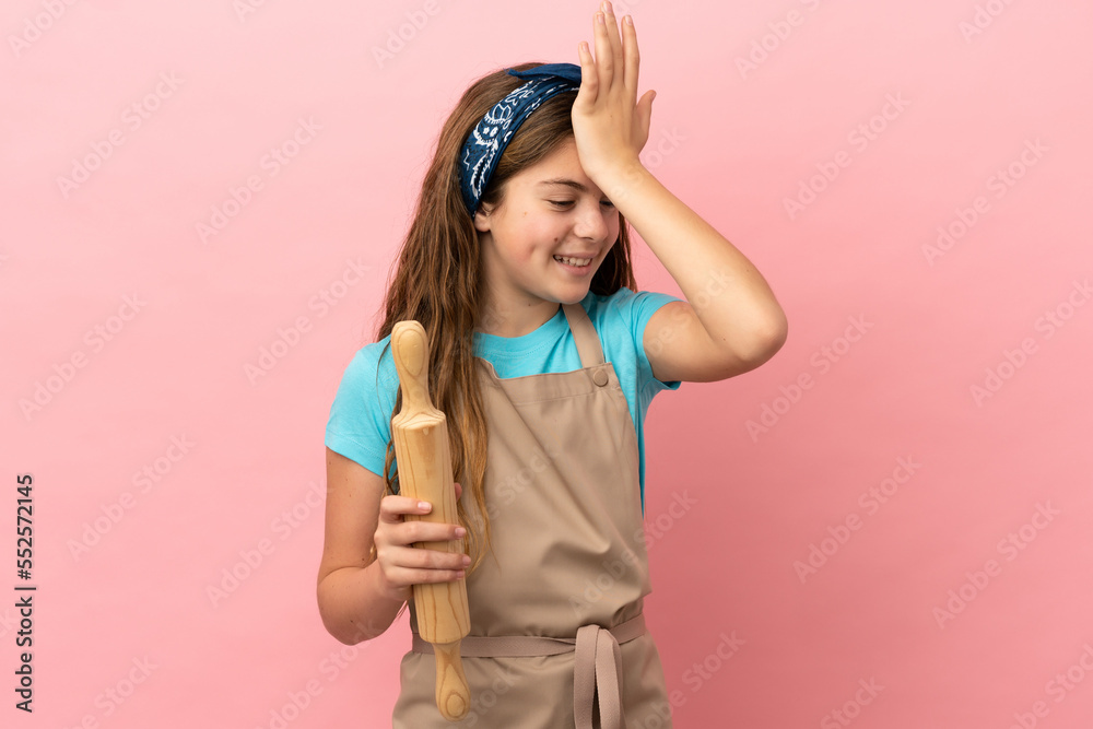 Little caucasian girl holding a rolling pin isolated on pink background has realized something and intending the solution Little caucasian girl holding a rolling pin isolated on pink background has realized something and intending the solution