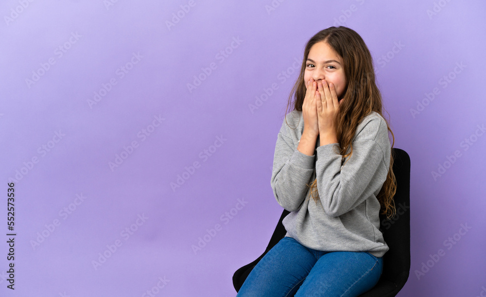 Little caucasian girl sitting on a chair isolated on purple background happy and smiling covering mouth with hands Little caucasian girl sitting on a chair isolated on purple background happy and smiling covering mouth with hands