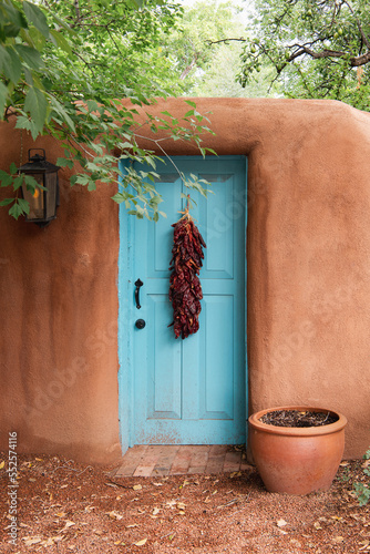 Turquoise door with chile ristra in adobe wall in Santa Fe, New Mexico