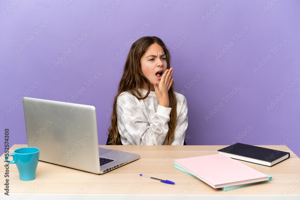 Little student girl in a workplace with a laptop isolated on purple background yawning and covering wide open mouth with hand Little student girl in a workplace with a laptop isolated on purple background yawning and covering wide open mouth with hand
